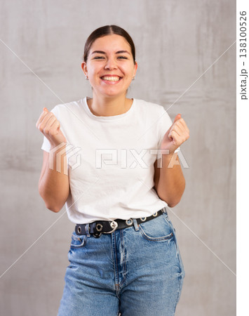 Cheery young woman posing happily against gray background 138100526