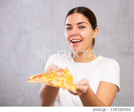 Pleased young woman holding piece of pizza Pleased young woman holding piece of pizza 138100588