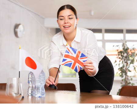 Young female attendant putting up flags for international negotiations between japan and united kingdom Young female attendant putting up flags for international negotiations between japan and united kingdom 138100642