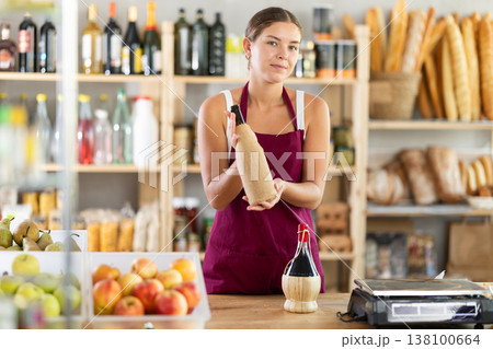 Young female seller offering wine in grocery store Young female seller offering wine in grocery store 138100664
