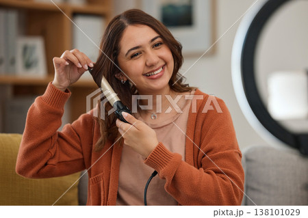 Hair care, curling iron and woman with smile for wellness, beauty treatment and cosmetics on sofa at home. Hairdresser, salon aesthetic and face of person with product for glow and healthy hairstyle 138101029