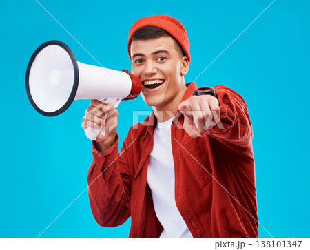 Portrait, bullhorn and young man in studio pointing for an announcement or speech at a rally. Happy, smile and male activist on stool with megaphone for loud communication isolated by blue background Portrait, bullhorn and young man in studio pointing for an announcement or speech at a rally. Happy, smile and male activist on stool with megaphone for loud communication isolated by blue background 138101347