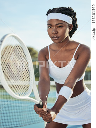 Sports, portrait and woman tennis player with a racket practicing to play a match at stadium. Fitness, serious and professional African female athlete with equipment training on court for tournament. Sports, portrait and woman tennis player with a racket practicing to play a match at stadium. Fitness, serious and professional African female athlete with equipment training on court for tournament. 138101560