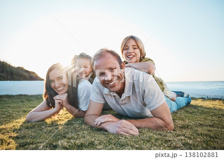 Family, parents and portrait of children on grass by ocean for bonding, relationship and relax together. Nature, sunlight and happy mother, father and kids on holiday, vacation and travel by sea Family, parents and portrait of children on grass by ocean for bonding, relationship and relax together. Nature, sunlight and happy mother, father and kids on holiday, vacation and travel by sea 138102881