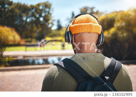 Back, music headphones and student outdoor, listening to audio or streaming sound online. Radio, podcast and man at park in nature, walking and hearing education media at university campus or college Back, music headphones and student outdoor, listening to audio or streaming sound online. Radio, podcast and man at park in nature, walking and hearing education media at university campus or college 138102995