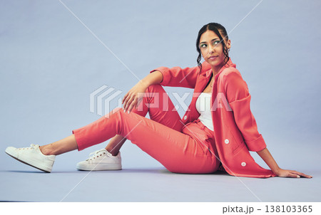 Woman, fashion and sitting on floor in studio with thinking face and makeup for beauty, aesthetic and cosmetics with mockup space. Smile, person and creative clothes on purple background with glow 138103365