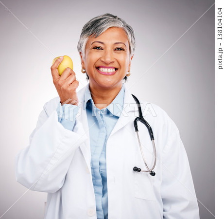 Woman, doctor and portrait with apple in studio for vitamin c benefits, health and care on grey background. Happy mature dietician, nutritionist and healthy food to lose weight with fruits for detox 138104104