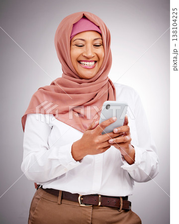 Muslim, phone and woman with smile in studio for social media scroll, internet post or mobile app on gray background. Smartphone, islam and person with happiness for technology, digital web or joy 138104225