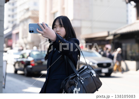 青春の1ページ。歴史ある街角でスマホを掲げ、セルフィーを撮る女子中学生のエモーショナルな光景 138105083
