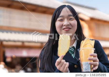 小江戸・川越のレトロな建物を背景に、名物の芋チップスを楽しむ制服姿の女子学生 小江戸・川越のレトロな建物を背景に、名物の芋チップスを楽しむ制服姿の女子学生 138105095