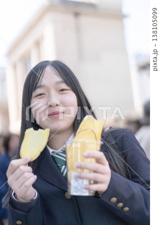 小江戸・川越のレトロな建物を背景に、名物の芋チップスを楽しむ制服姿の女子学生 小江戸・川越のレトロな建物を背景に、名物の芋チップスを楽しむ制服姿の女子学生 138105099