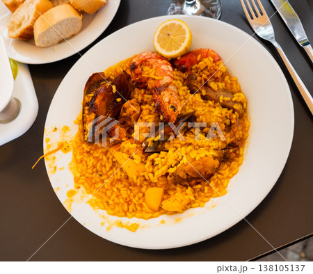 Plate is filled with paella made according to Spanish recipe from rice cereals, seafood, and chicken Plate is filled with paella made according to Spanish recipe from rice cereals, seafood, and chicken 138105137
