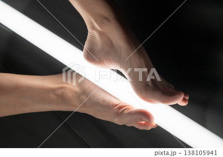 A woman holds an LED lamp with her feet. Foot fetish. A woman holds an LED lamp with her feet. Foot fetish. 138105941