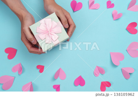 Hands holding a gift box with pink bow and hearts Hands holding a gift box with pink bow and hearts 138105962