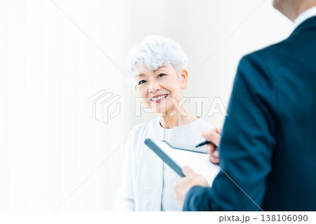 営業マンの説明を聞くシニア女性 138106090