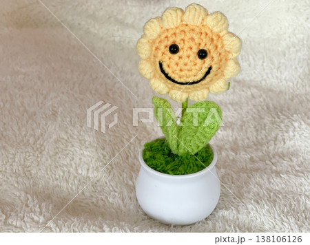 Handmade Crochet Sunflower In Pot With Smiling Face On White Fur Background Handmade Crochet Sunflower In Pot With Smiling Face On White Fur Background 138106126