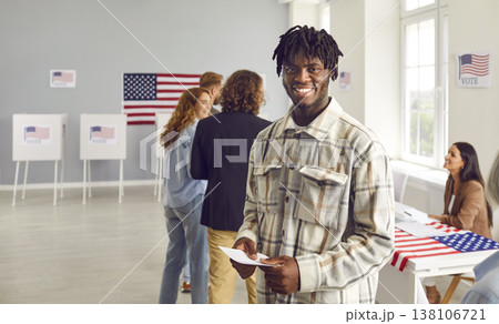 Young happy american voter standing in a queue at vote center and looking cheerful at the camera. 138106721