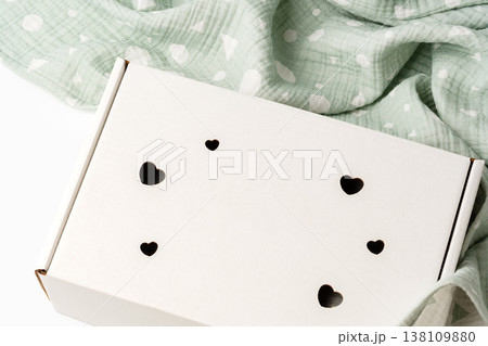 Gift box with heart cutouts on a soft, patterned blanket in a bright room Gift box with heart cutouts on a soft, patterned blanket in a bright room 138109880
