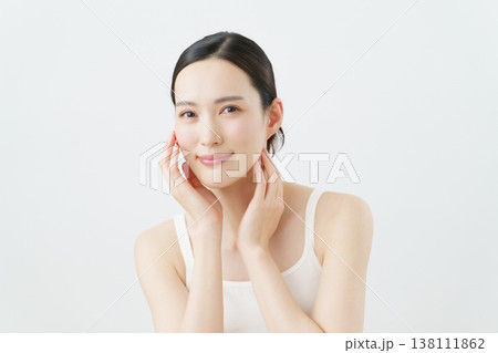 白背景の頬に手を当てる若い女性のスキンケアイメージ 138111862