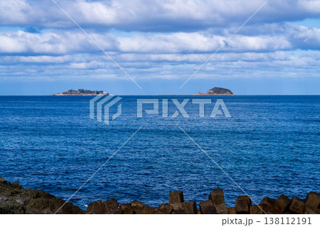 青空の下、遠くの海に浮かぶ軍艦島の全景 138112191