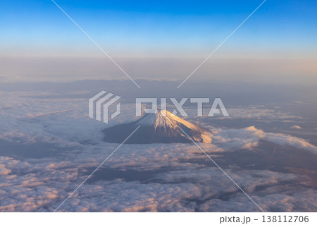 飛行機の機窓から、雲から頭を突き出す富士山 138112706