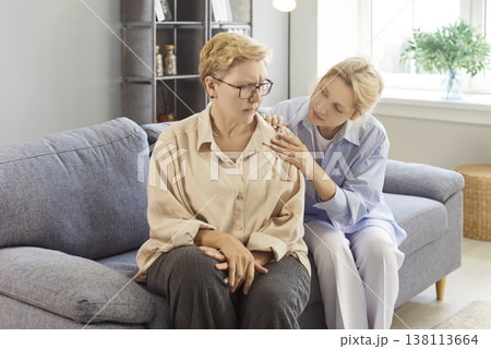 Senior upset mother and adult daughter sitting on sofa at home, helping offering comfort, caring Senior upset mother and adult daughter sitting on sofa at home, helping offering comfort, caring 138113664