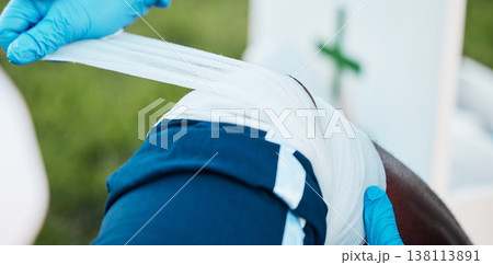 Sports, injury and person with bandage for knee pain, emergency and first aid for muscle sprain. Fitness, healthcare and medic with athlete with accident from exercise, workout and training outdoors Sports, injury and person with bandage for knee pain, emergency and first aid for muscle sprain. Fitness, healthcare and medic with athlete with accident from exercise, workout and training outdoors 138113891