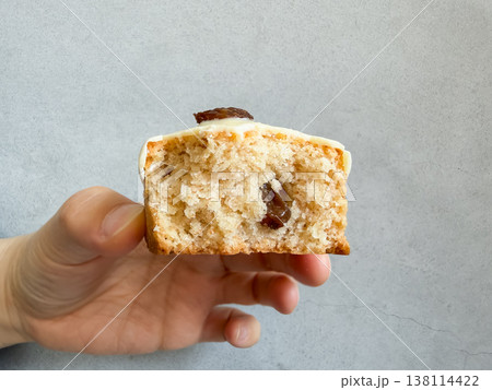 手で持った焼き菓子のスコーン。ラムレーズンとホワイトチョコレート。断面。 138114422