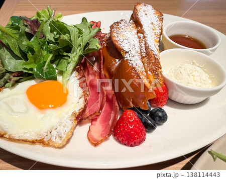フレンチトーストとベーコンと目玉焼きが乗ったプレート料理。 フレンチトーストとベーコンと目玉焼きが乗ったプレート料理。 138114443
