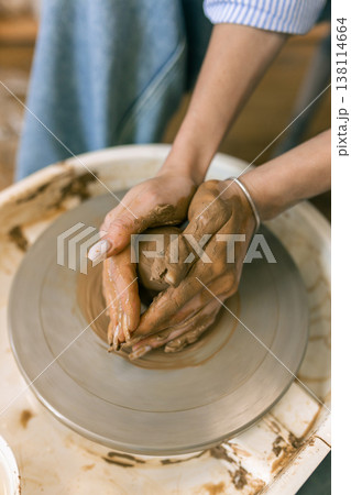 Close up of female hands shaping clay on pottery wheel in ceramic studio, handmade pottery process and traditional craft Close up of female hands shaping clay on pottery wheel in ceramic studio, handmade pottery process and traditional craft 138114664