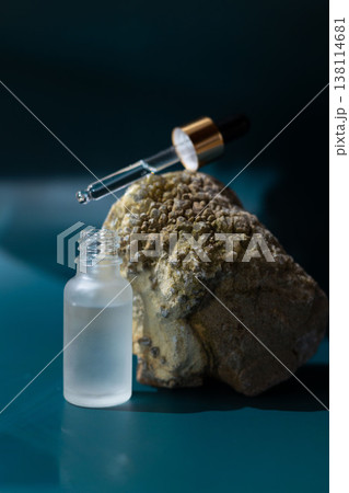 Frosted glass cosmetic dropper bottle on natural stone with dark blue background, skincare serum packaging mockup, minimal beauty product concept Frosted glass cosmetic dropper bottle on natural stone with dark blue background, skincare serum packaging mockup, minimal beauty product concept 138114681