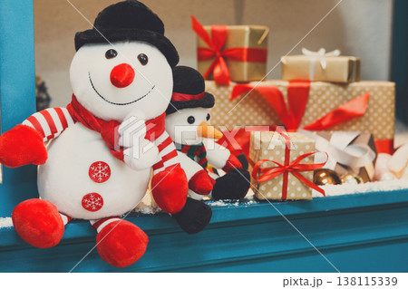 Cozy winter holidays background. Funny toy snowmen and presents waiting for christmas on blue wooden showcase . Joyful and magical atmosphere of new year eve, copy space 138115339