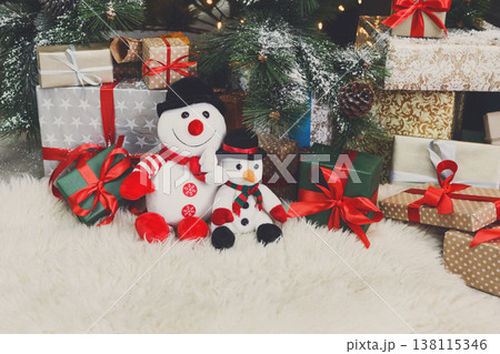 Cozy winter holidays background. Funny toy snowmen and presents waiting for christmas under decorated fir tree. Joyful and magical atmosphere of new year eve, copy space 138115346