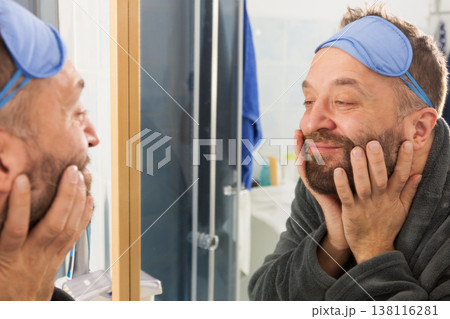 Happy man after sleep looking at mirror Happy man after sleep looking at mirror 138116281