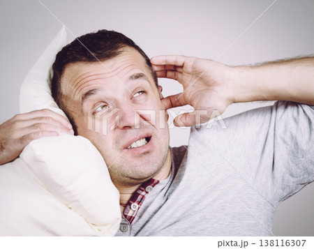 Sleepy man with pillow closing his ear Sleepy man with pillow closing his ear 138116307