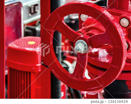 Close-up view of a red valve wheel on machinery in an industrial site during daylight hours Close-up view of a red valve wheel on machinery in an industrial site during daylight hours 138116429