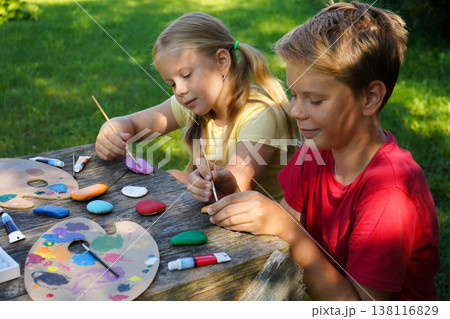 Children carefully decorate smooth, flat stones, crafting cheerful gifts filled with their artistic spirit and joy. Children carefully decorate smooth, flat stones, crafting cheerful gifts filled with their artistic spirit and joy. 138116829