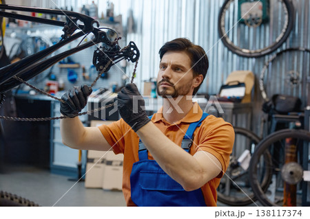 Technician carefully adjusts chains in workshop 138117374