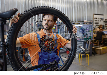 Technician analyzing bike wheel in repair shop environment 138117382