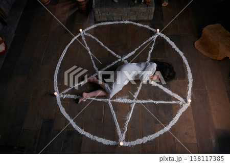 Battered female figure surrounded by candles after spiritual ritual 138117385
