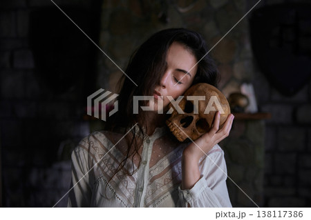 Enigmatic woman studies relic skulls in shadowed gothic room with mysterious ambiance Enigmatic woman studies relic skulls in shadowed gothic room with mysterious ambiance 138117386
