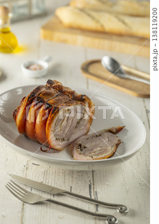 Traditional Italian porchetta with crispy skin on a white plate Traditional Italian porchetta with crispy skin on a white plate 138119200