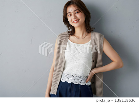刺繍ブラウスにニットベストを重ね軽やかに微笑む女性 138119636