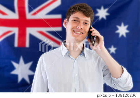 Young guy talking on phone in front of Australian flag Young guy talking on phone in front of Australian flag 138120230