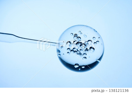 Abstract cosmetic lab. Pipette drawing clear liquid from spherical gel with bubbles 138121136