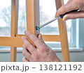 Hands Using Screwdriver to Assemble Wooden Chair at Home 138121192