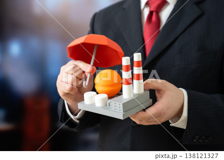 A businessman holds an umbrella over an industrial facility. Protecting the energy sector from drones and threats. Industrial insurance. Chemical sector. Risk mitigation and security planning A businessman holds an umbrella over an industrial facility. Protecting the energy sector from drones and threats. Industrial insurance. Chemical sector. Risk mitigation and security planning 138121327
