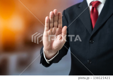 A businessman holds up his palm to indicate a halt. A stop sign. Stop and listen to advice. Prohibitions and sanctions. Risk control and regulation prevent negative outcomes. A businessman holds up his palm to indicate a halt. A stop sign. Stop and listen to advice. Prohibitions and sanctions. Risk control and regulation prevent negative outcomes. 138121421