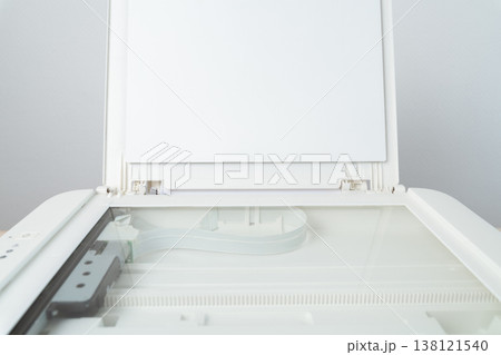 Open flatbed scanner with exposed glass platen and raised lid in a clean modern office, ideal for document scanning, copying and digital archiving, close-up of the empty scanning bed and mechanism. Open flatbed scanner with exposed glass platen and raised lid in a clean modern office, ideal for document scanning, copying and digital archiving, close-up of the empty scanning bed and mechanism. 138121540