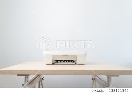 White all-in-one printer sits centered on a light wooden desk against a soft neutral wall, conveying minimalism, calm and productivity in a modern home office or small business workspace. 138121542